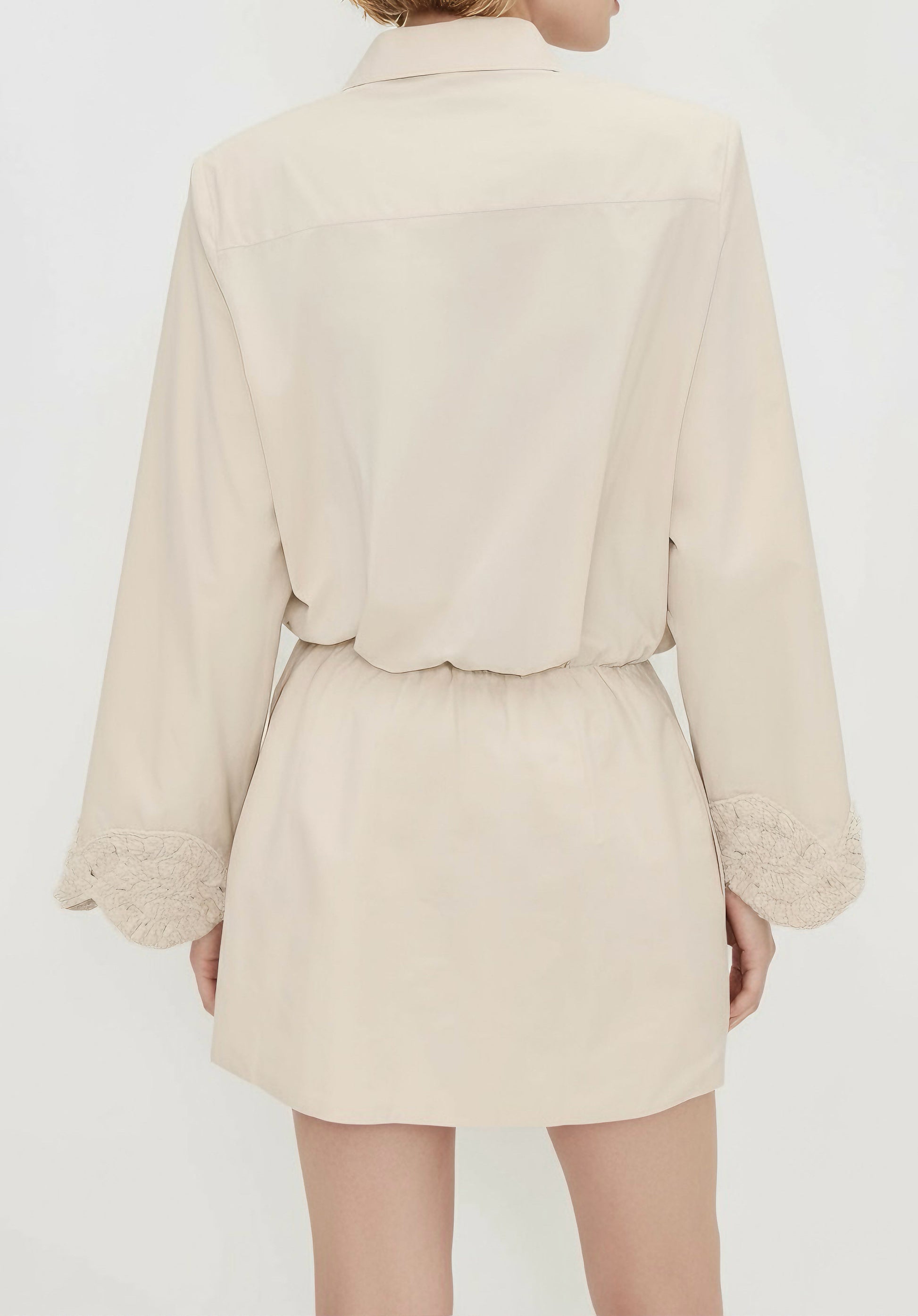 Beige tailored mini dress with structured collar, button-down front, and crochet embroidered sleeve hems.