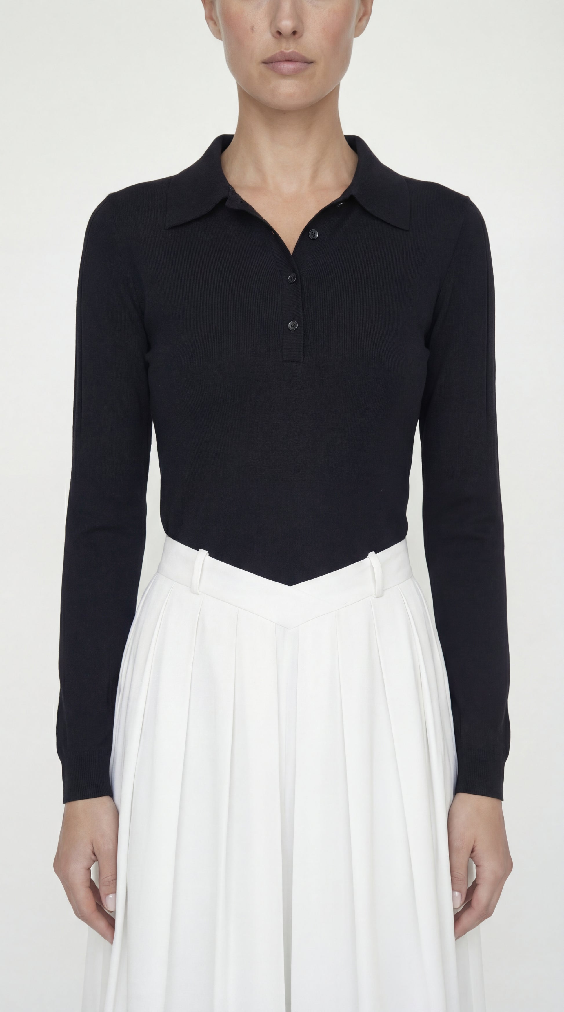 Detailed close-up of the textured knit polo collar and the crisp, structured twill fabric of the pleated skirt.