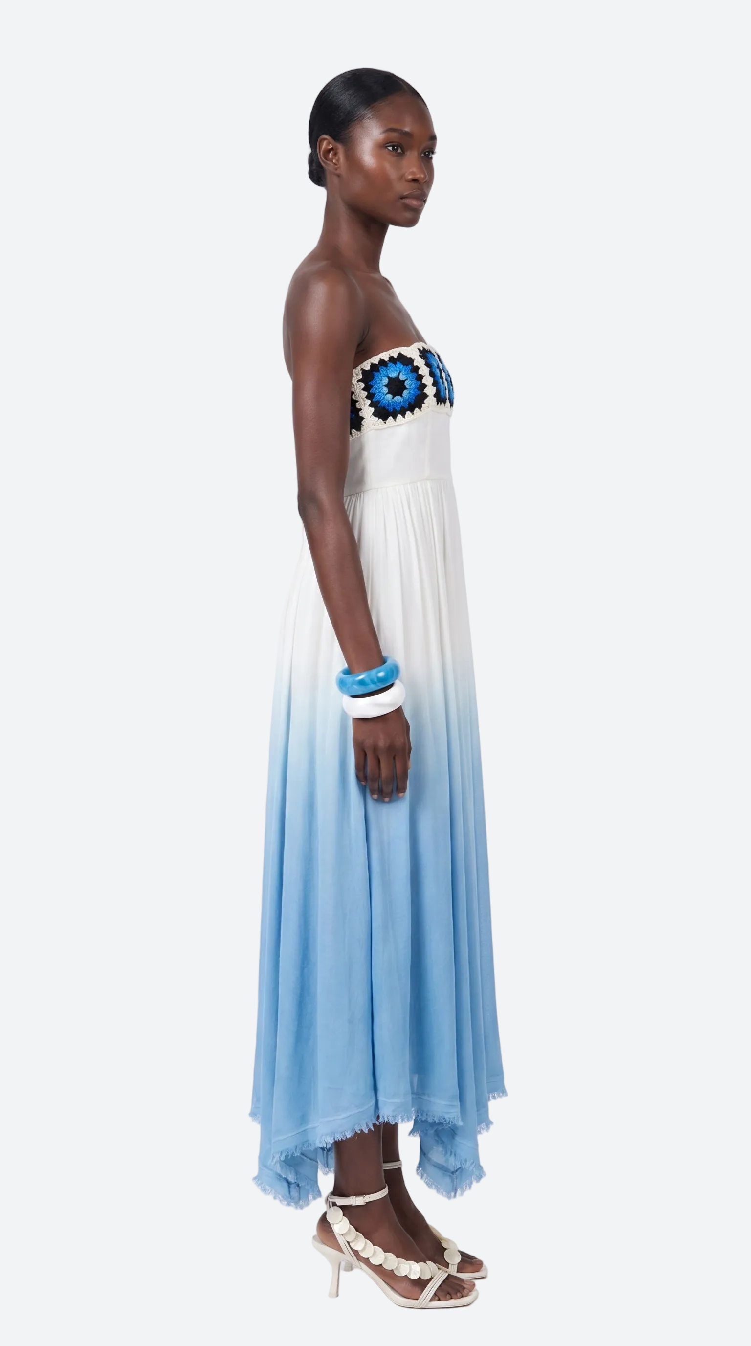 Woman wearing a strapless elexiay evil eye dress with a blue and white gradient on a white background