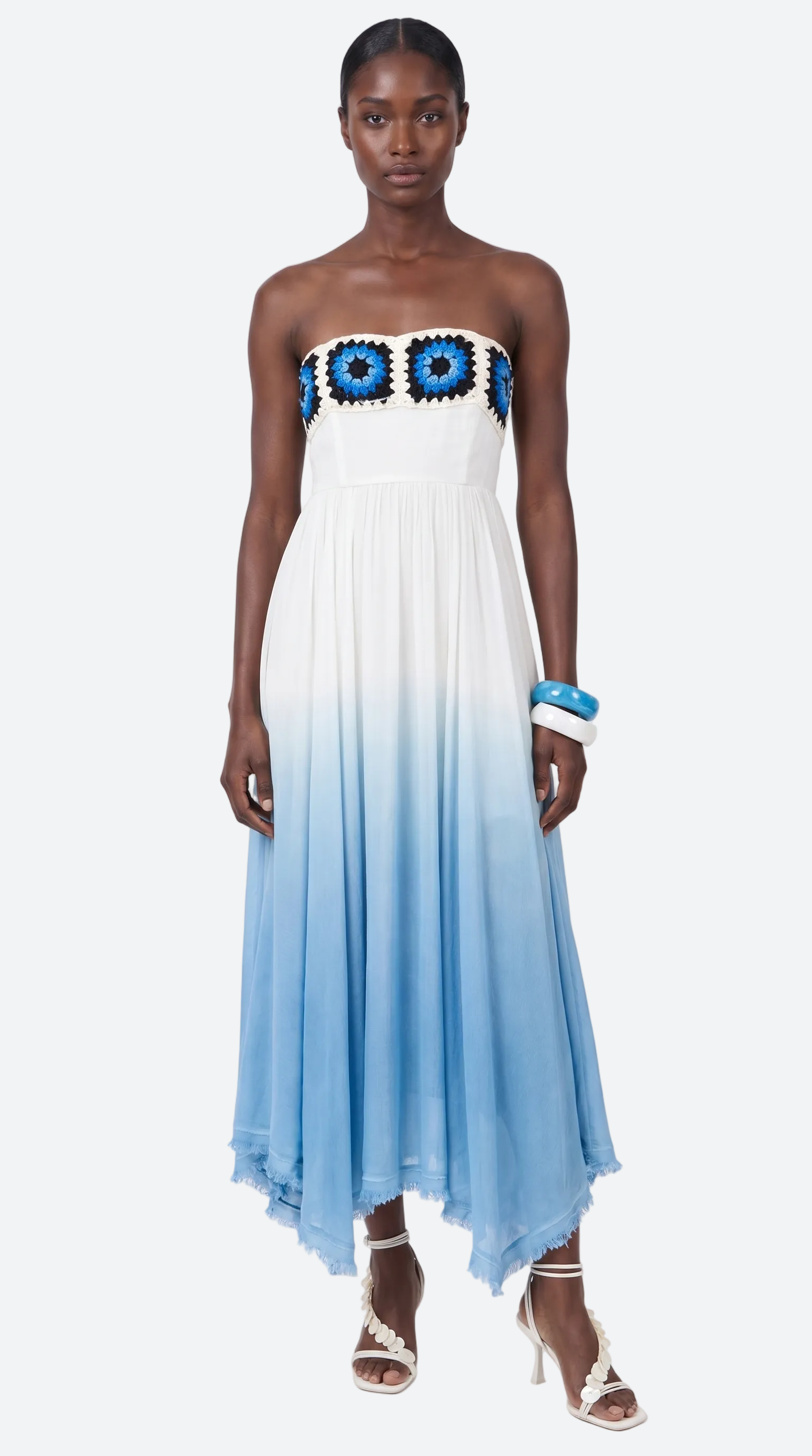 Woman wearing a strapless evil eye elexiay dress with blue floral top and gradient blue to white skirt on a white background 